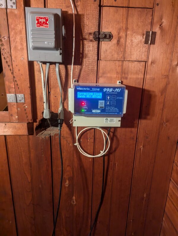 Electric Time tower clock controller mounted on a wooden wall, displaying time correction details